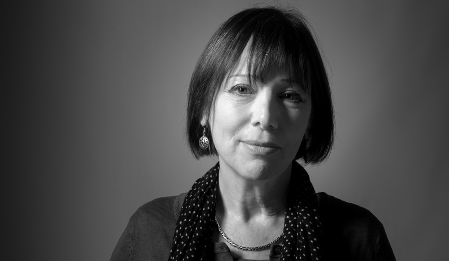 A monochromatic portrait of female lecturer Dr Anne Karpf smiling to the camera.