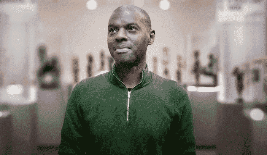 Headshot of Dr Akande wearing a green jumper, smiling 