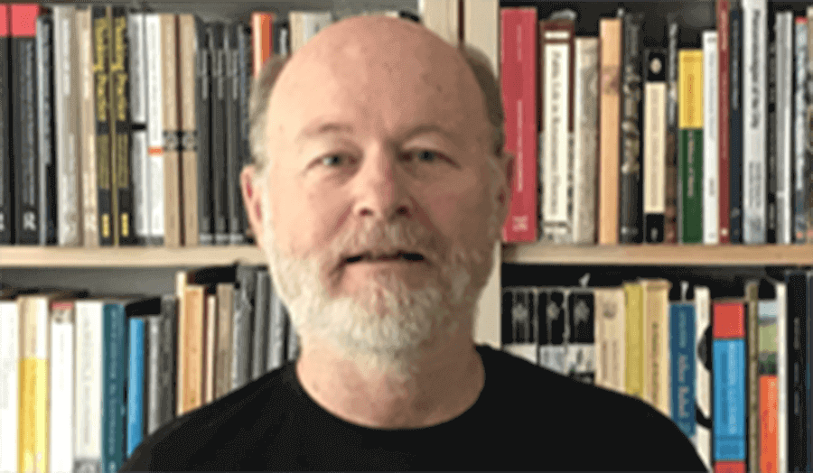 Nicholas Temple in front of a bookshelf smiling at the camera 