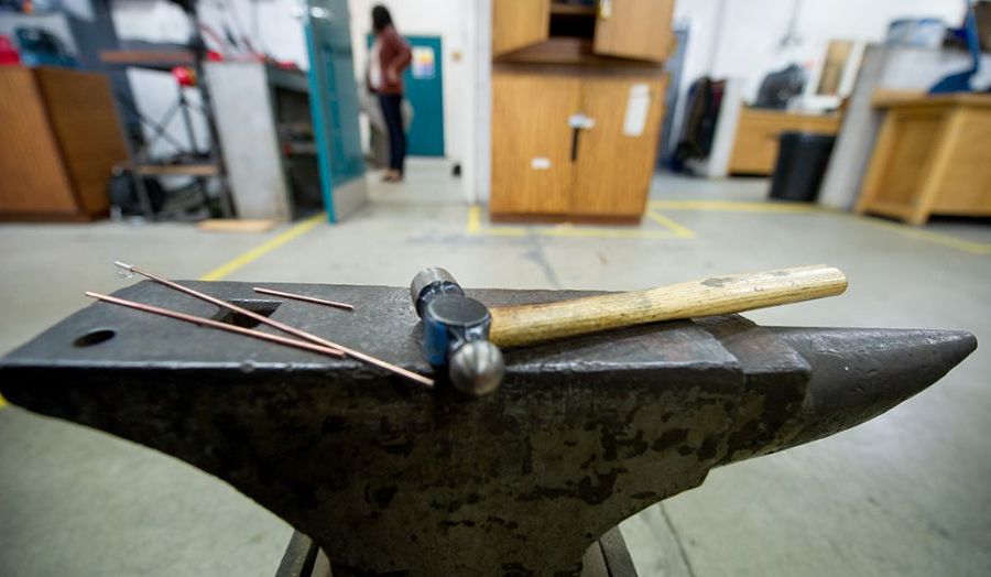 Photograph of a hammer on top of an anvil inside a workshop 