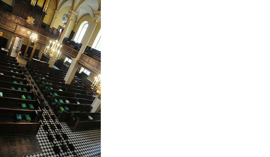 Empty pew and a black and white tiled floor in a church