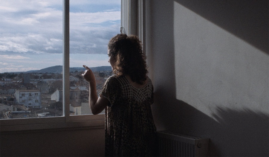 Still from film showing woman looking out of window