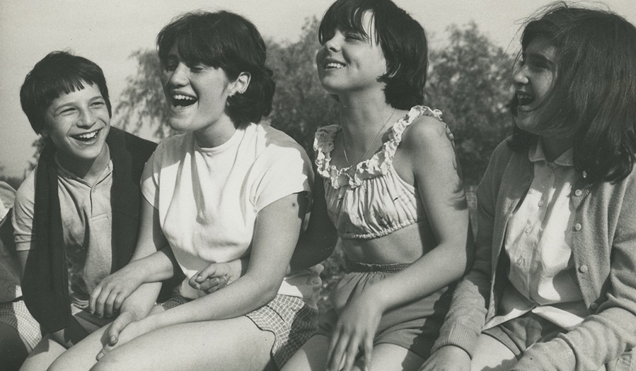 black and white image of four  girls on a wall 