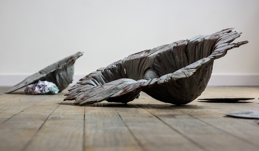 two bowl shaped sculptures  exhibited on a wooden floor