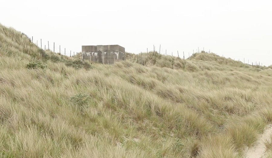 concrete pill box building on top of a grassy slope