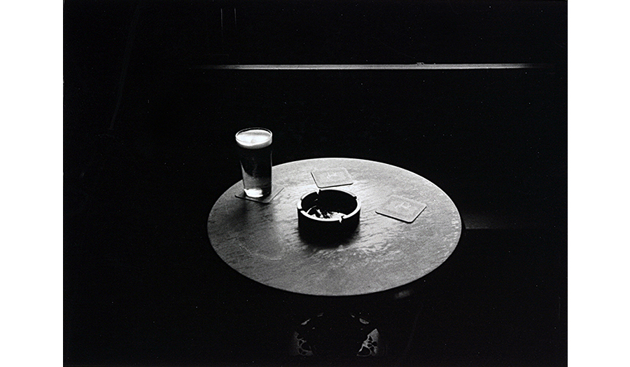 Table with a half pint of beer and an ashtray