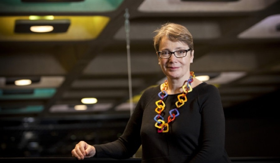 woman in coloured necklace faces camera