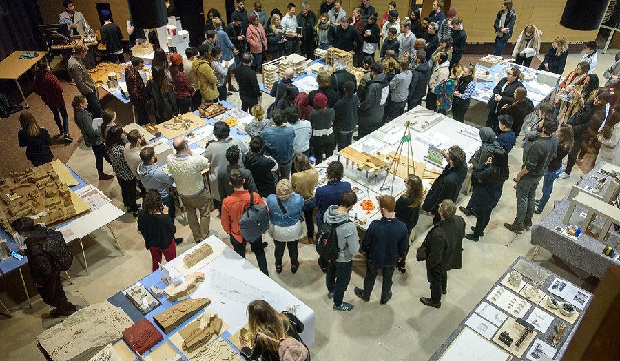 a large group of people in a room full of architectural models, viwed from above