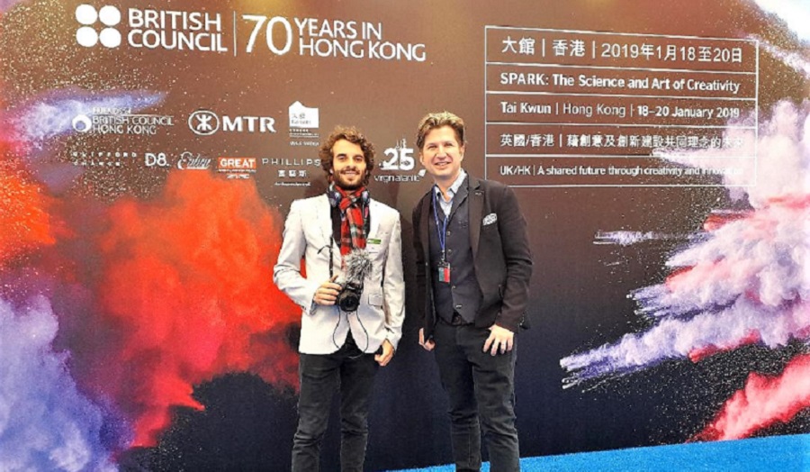 two men in front of a billboard advertising spark festival in hong kong