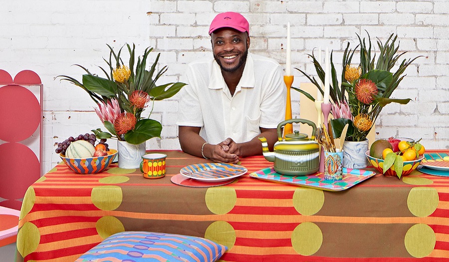 A man sits at a table covered in colourful homeware design products