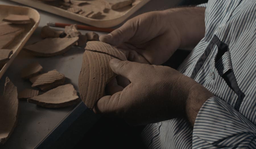 Hands holding pieces of terracotta fragments