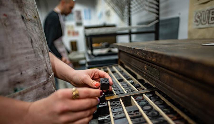 Close up of hands handling letterpress metal plates