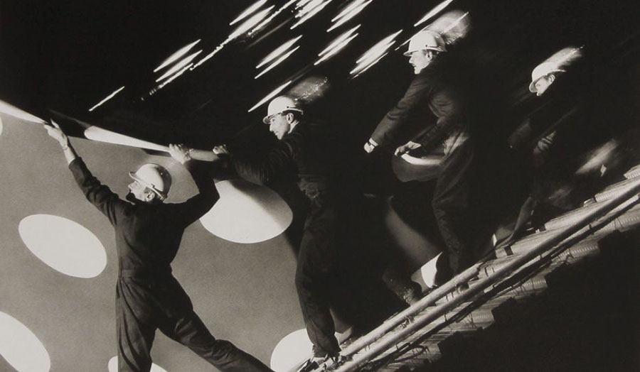 A surreal photo of construction workers unrolling a poster with giant dots by Brian Griffen