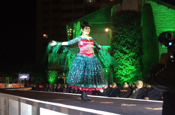 A woman in traditional South American dress walks on a catwalk