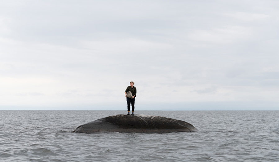 A person standing on a rock in the middle of the sea