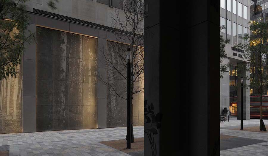 The external of a contemporary concrete building with projections of silver birch trees on it