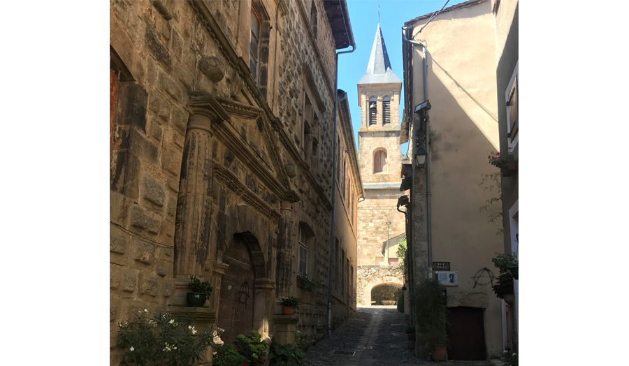 Cobbled lane with medieval stone buildings and church spire