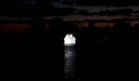 Small white house floating in water at night with clouds