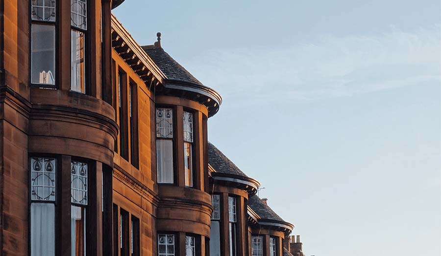 Top of red sandstone tenement buildings in Glasgow showing the bay windows and turrets.