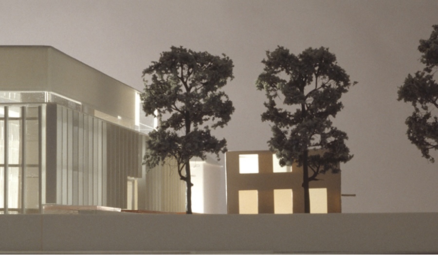 Architectural model showing a glass building beside a simpler structure with three detailed trees.