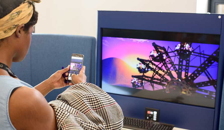 Student using her phone to mirror and image of a ferris wheel onto a television monitor