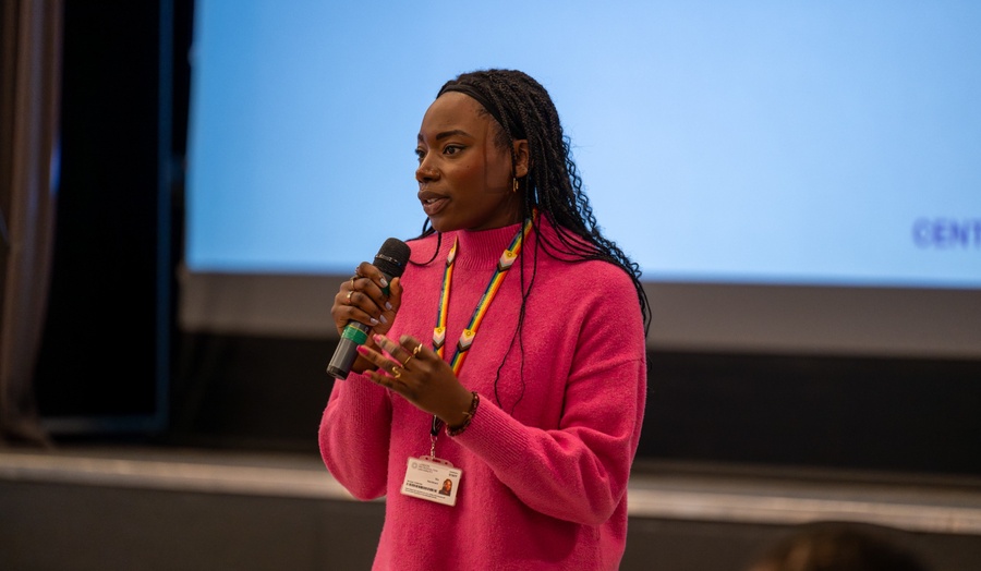 Woman speaking into a microphone at a staff networking event. 