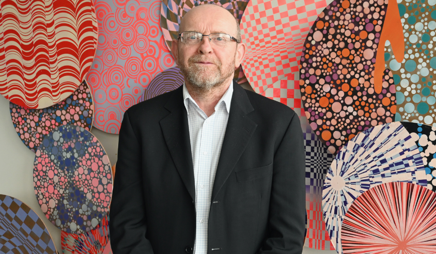 Image of Michael Upton standing in front of an abstract art piece