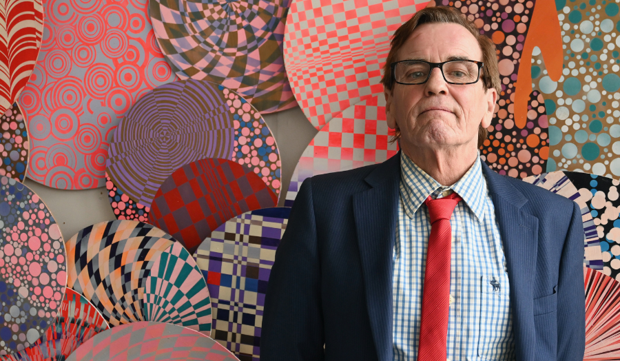 Tom Burns standing against an abstract art background
