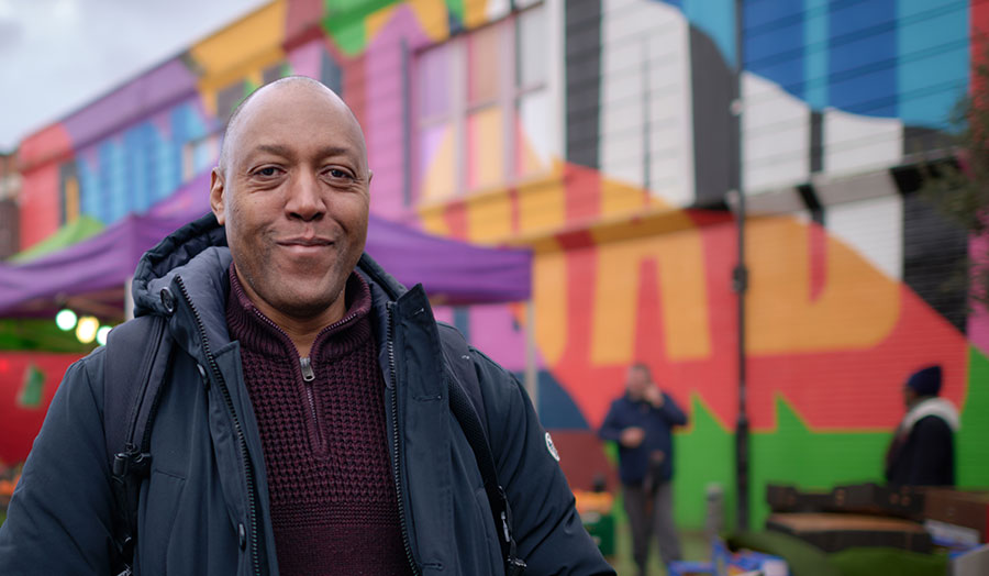 Don smiling outside colourful backdrop at Ridley Road market