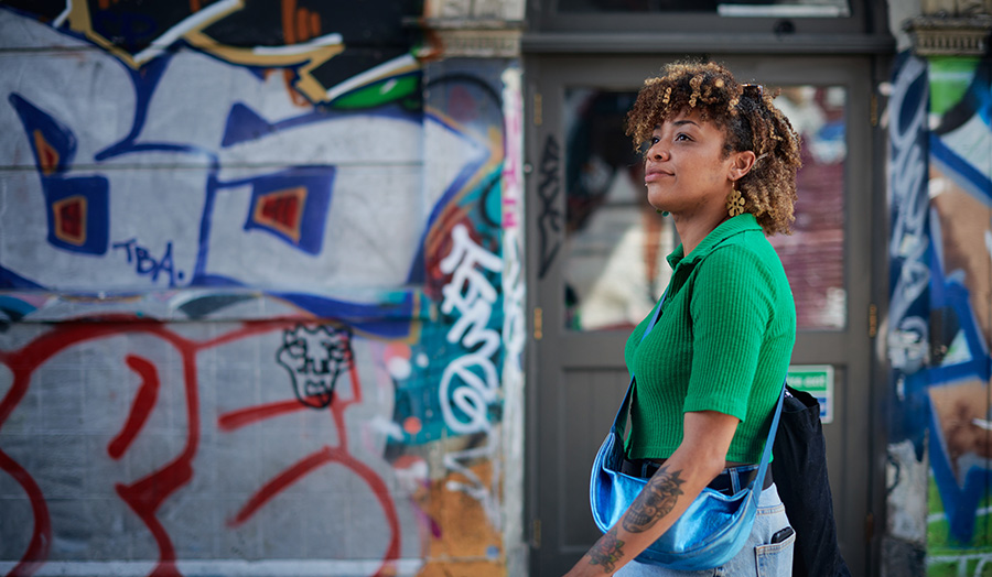 A woman in a green top standing in front of a wall full of graffiti