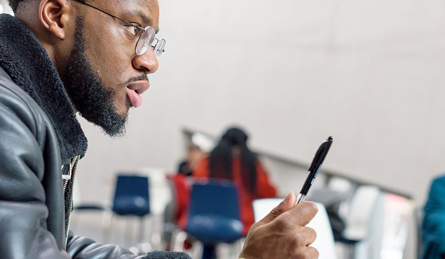 Black student in graduate centre holding pen