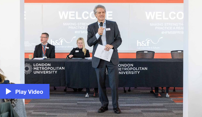 Man standing in front of a conference panel speaking to an audience