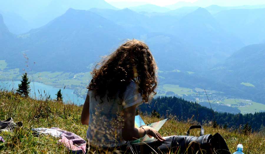 Fine art student sat at the top of a hill sketching the scenery