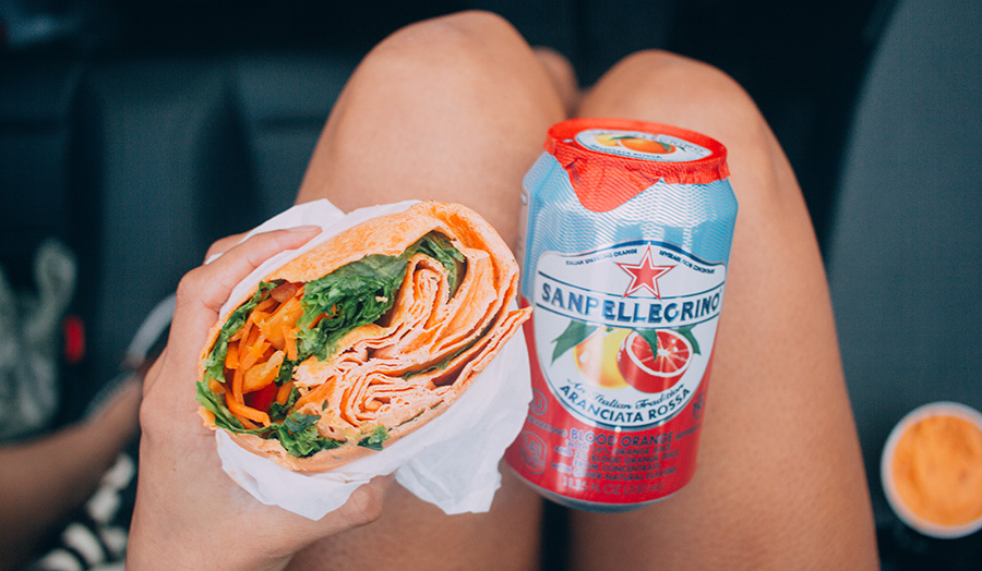 A girl holding a wrap and a fizzy drink