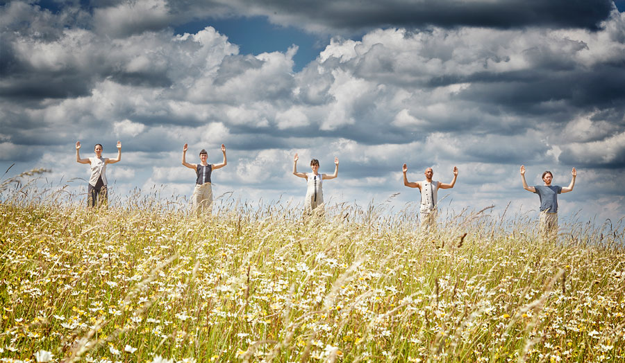 Five dancers standing on a hill