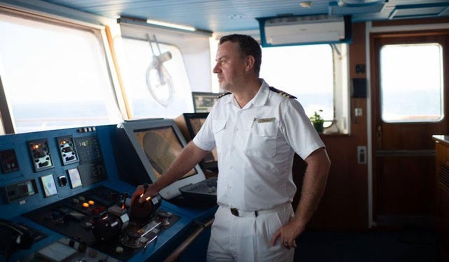 captain on ship holding wheel