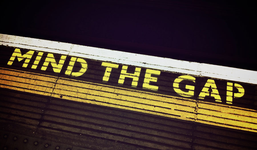 A yellow 'mind the gap' sign painted on an underground tube platform in