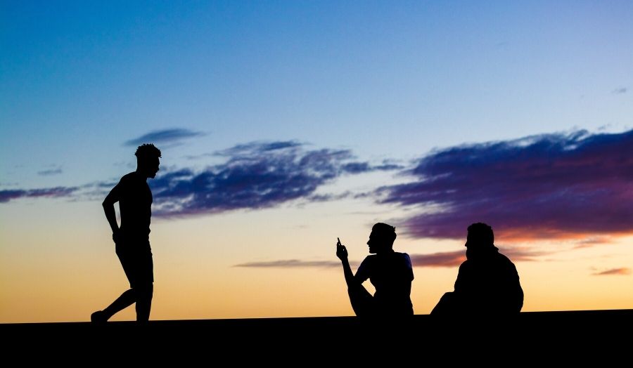 Three teenagers silhouetted in front of an evening sky.