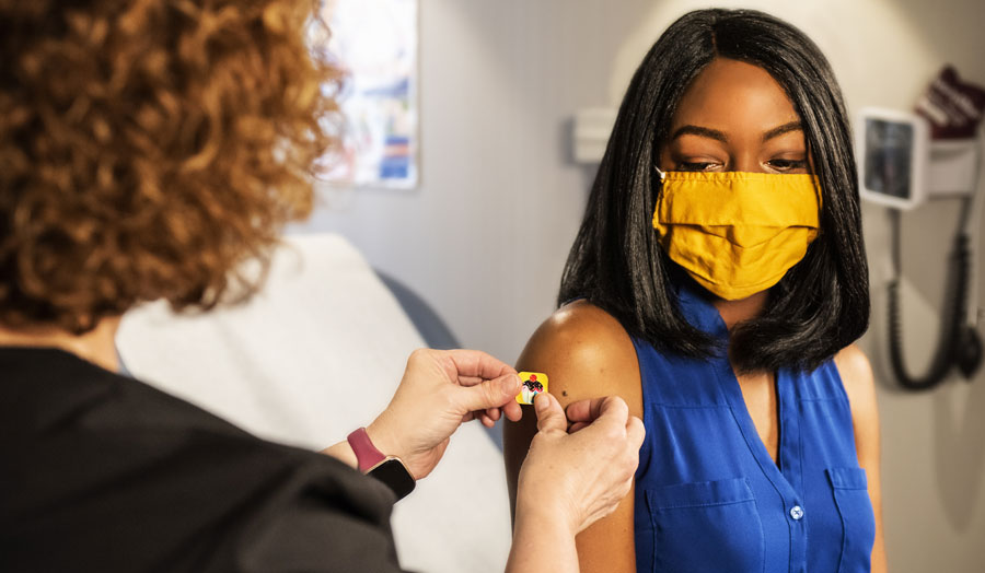 a woman having a plaster applied to her arm after a vaccine
