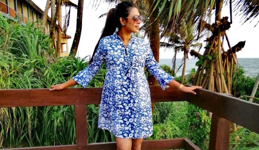 woman wearing blue dress leaning against fence