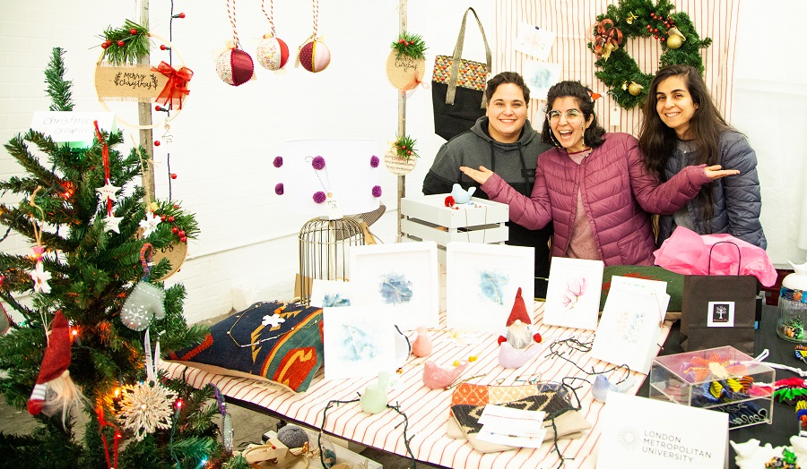 three people behind a Christmas themed stall