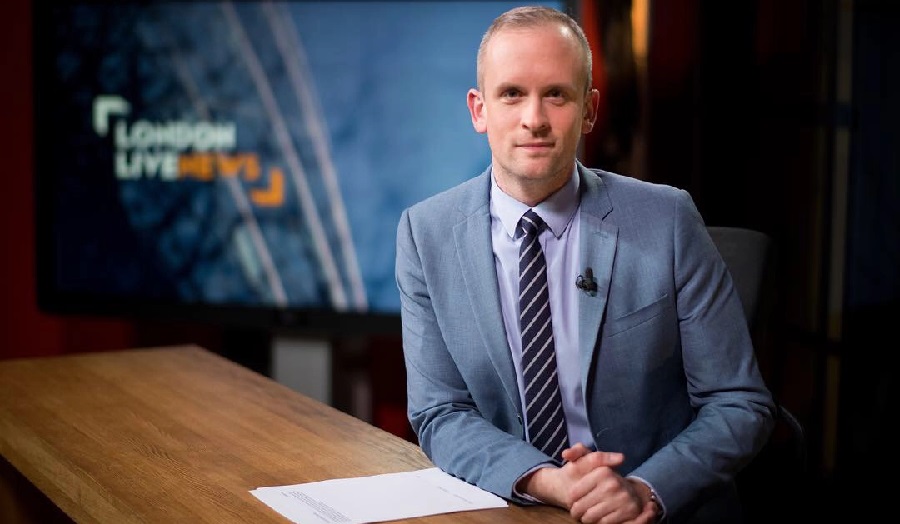 man sitting behind a desk, wearing a suit