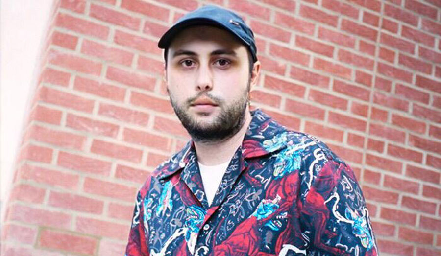 man wearing baseball cap in front of brick wall