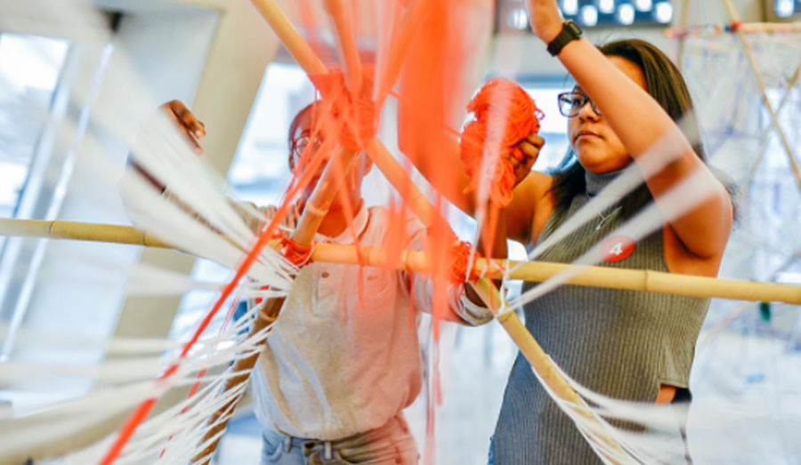 Two children making a sculpture out of string