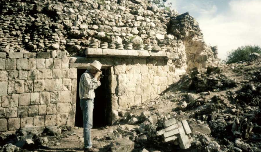 man looking into a camera in front of a stone building