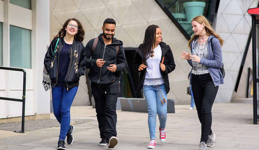 group of three women and one man walking and laughing