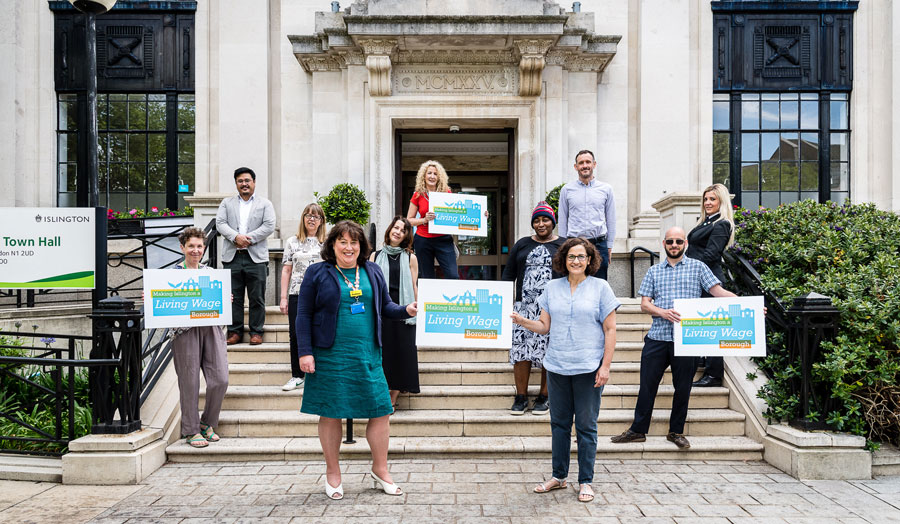 group of people standing on steps holding signs saying 'London Living Wage'