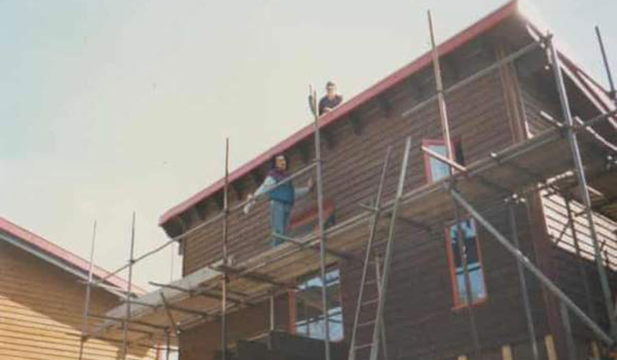 old fashioned image of a man on scaffolding outside a house