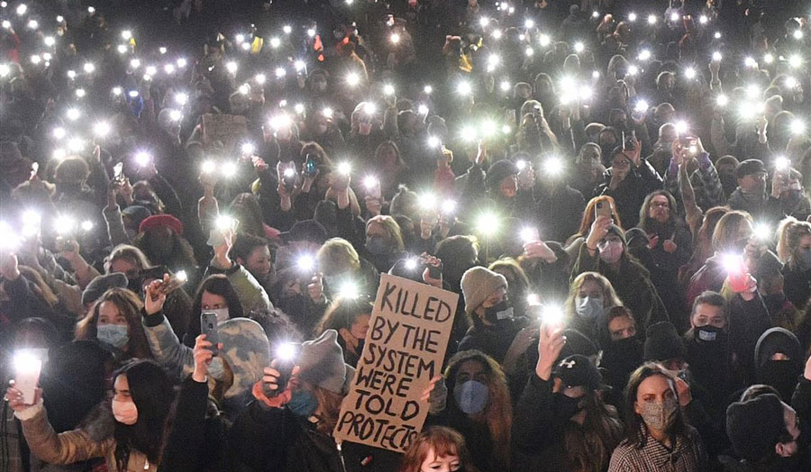 group of women holding the light of their phones up in the darkness