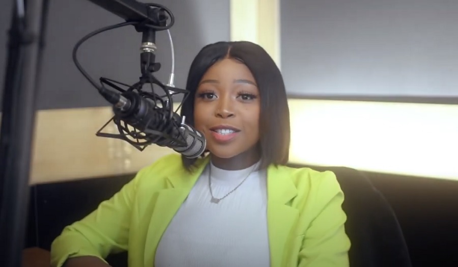 woman in a recording booth, speaking into a microphone